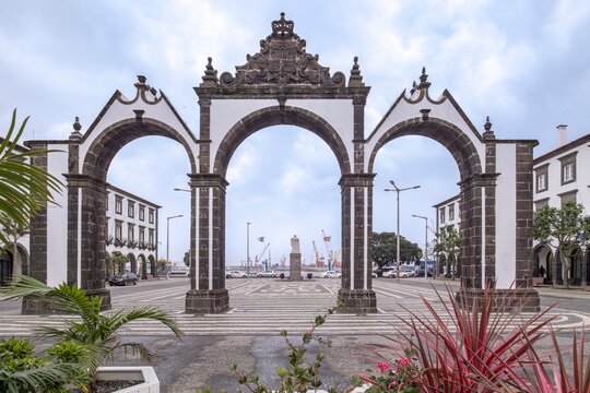 Portas da Cidade Triple Arches Framing Ponta Delgada Harbor View in Sao Miguel Azores. Portuguese colonial gateway, volcanic stone construction, Atlantic waterfront