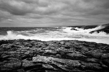 Vagues frappant des rochers sur une c&ocirc;te en noir et blanc
