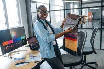 Woman is holding colorful palette. Designer is working in the office