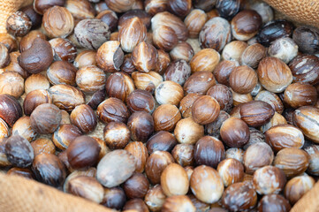 Nutmeg heap, fruit seed and ground spice, market stall in India, spicy food ingredient for sale in...