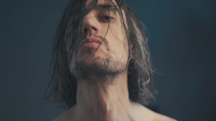 Intense Close-Up Portrait of a Pensive Man with Tousled Hair and Edgy Expressions Against a Deep Blue Background