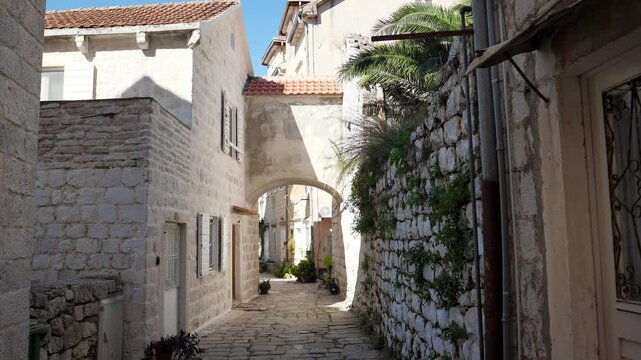 Warm sunlight illuminating narrow cobblestone street, revealing weathered stone buildings in historic perast, montenegro charming mediterranean architectural landscape. Travel destinations.