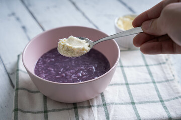 ube champorado topped with milk powder; a sweetened flavored porridge that are famous among Filipinos