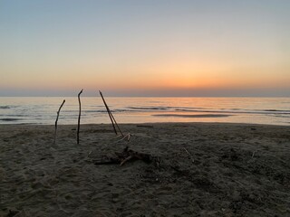 Driftwood forming a small hut on the beach at sunset in Pineto, Abruzzo, Italy, creating a peaceful and evocative scene