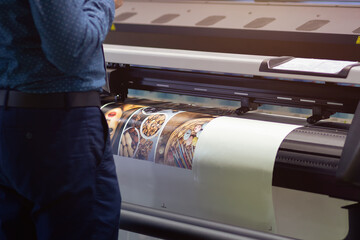 Industrial printing machine prints colorful poster in factory