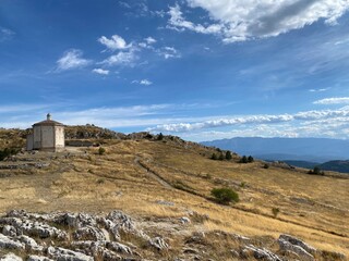 Scenic view of Santa Maria della Pietà, a 16th-century octagonal church, overlooking the ruins of Rocca Calascio with the Gran Sasso mountains in the background, Abruzzo, Italy