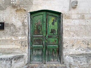 Weathered green wooden door gracing an old house in Matera, Basilicata, Italy, showcasing rich textures and a sense of history