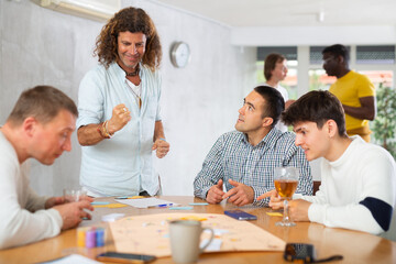 Obraz premium Group of men play board games during a friendly meeting indoors
