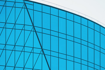 Fototapeta premium Modern architectural building showcasing curved glass facade in bright daylight with geometric pattern