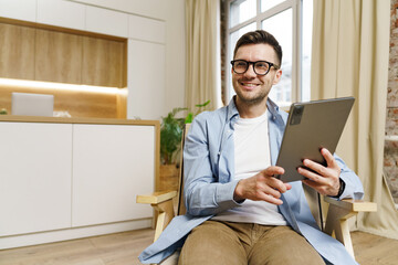 Joyful individual enjoying tablet engagement in a cozy and stylish indoor space with natural light