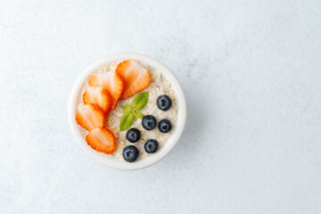 Top view of oatmeal with strawberries and blueberries on white background