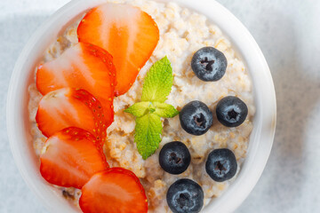 Close up of oatmeal bowl with strawberries blueberries and mint