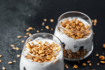 Parfaits with granola and yogurt in glass on dark  background