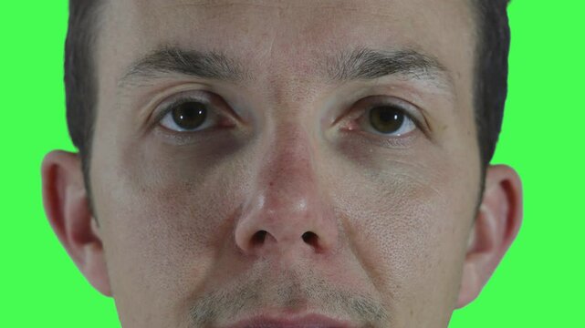 A man in a neutral, emotionless state looks straight ahead, with steady eyes and expressionless face, shot in studio against chroma green. Useful as base footage.