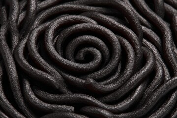 Swirling strands of thick, dark pasta in a spiral formation, creating a visually captivating and textured food arrangement
