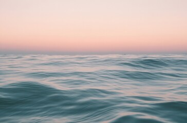 Obraz premium Peaceful sunrise over calm ocean waves, soft pink and orange sky