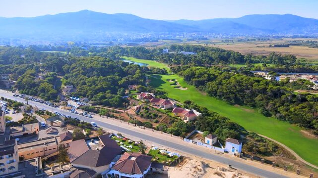 This 4K aerial stock footage captures a lush green golf course in the beautiful location of Tabarka,The scenic golf course is filled with many trees and houses, creating an idyllic atmosphere