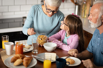 Grandparents with granddaughter having breakfast together