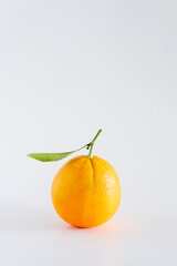 A fresh, rich and healthy orange with leaf resting on white background