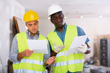 Two engineers discussing blueprints in a renovated room