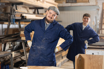 Two young male workers in carpentry workshop warm up while working ..