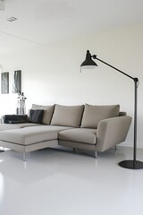 Black lamp is on a white floor next to a gray couch