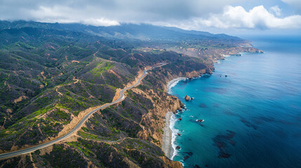 Obraz premium An awe-inspiring aerial view of a winding road cutting through mountains or a coastal landscape, depicting nature's grandeur