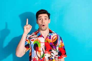 Excited young man making a surprise gesture with colorful shirt on blue background, expressing joy...