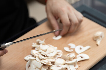 Cooking a dish of mushrooms champignons. Cut vegetables with a knife