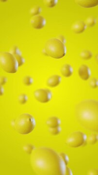 Lemons fall on a yellow background. Vertical looped video