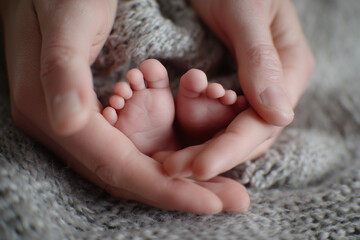 baby's feet are being held in a parent's hands. The baby is small and fragile, and the image conveys a sense of tenderness and protection