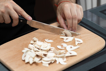 Cooking a dish of mushrooms champignons. Cut vegetables with a knife