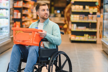 Customer using wheelchair holding shopping basket in supermarket