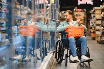 Customer using wheelchair choosing products in supermarket refrigerator section