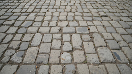 Close-up texture of aged cobblestone pavement, featuring irregular stones in natural earthy colors, rustic outdoor setting