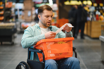 Customer in wheelchair checking grocery receipt in supermarket