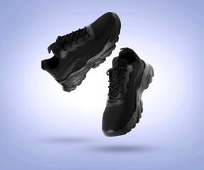 Stylish black sneakers in air on light blue gradient background
