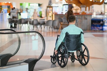 Obraz premium Customer using wheelchair looking at escalator in shopping mall