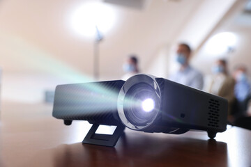 Modern video projector on table indoors, selective focus. Displaying image