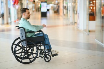 Man in wheelchair moving through shopping mall corridor
