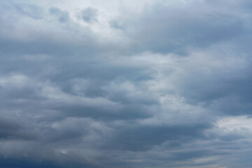 Obraz premium storm clouds gather across the blue sky during the rainy season, forming dramatic shapes as nature signals an approaching storm over the open landscape.