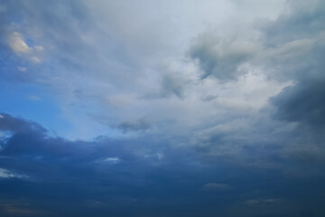 Obraz premium Dark storm clouds gather across the blue sky during the rainy season, forming dramatic shapes as nature signals an approaching storm over the open landscape.