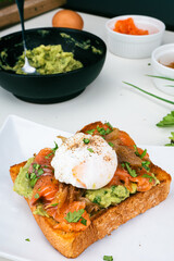 breakfast plate with poached eggs,  smoked salmon guacamole on toast homemade healthy and served on bread. Vertical photo