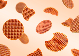 Yummy Dutch waffles (stroopwafels) flying on beige gradient background