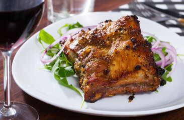 Delicious grilled rack of pork served with fresh arugula leaves and purple onion..