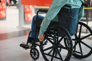 Customer using wheelchair moving around shopping mall during sales