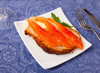 Light and healthy breakfast - sandwiches of bran bread and salmon, decorated with rucola. Light and hearty breakfast, healthy food, easily digestible protein