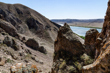 Mountain River Flowing Through Arid Canyon Valley with Rocky Slopes and Clear Blue Water