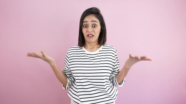 Clueless young woman looking at camera point finger at herself feel hesitates about something say who me shrugging shoulders don't know, who cares, demonstrating doubts, isolated over pink background.