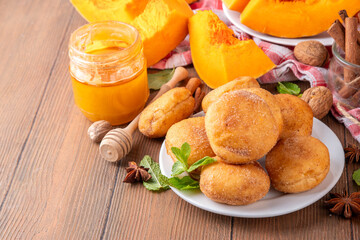 Autumn pumpkin pie donuts with cinnamon sugar sprinkled topping and pumpkin spice filling, on white wooden table with honey and pumpkin squash slices, copy space